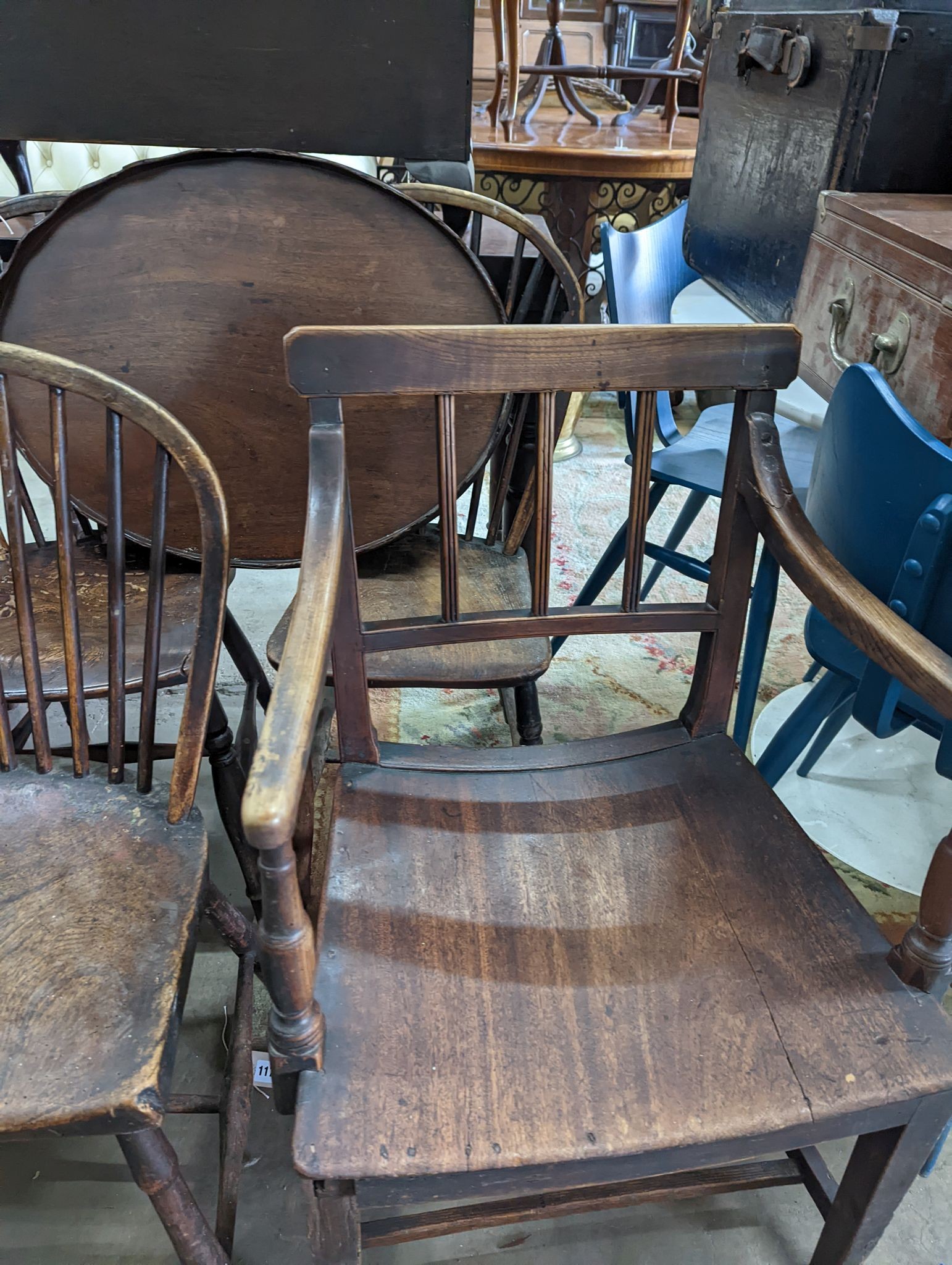 A 19th century elm and ash primitive Windsor comb back chair with traces of original paint, two other Windsor comb back chairs, a George III provincial elbow chair and an oval mahogany tea tray